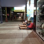 Backpacker sitzen abends vor einem Laden um das WIFI zu nutzen.